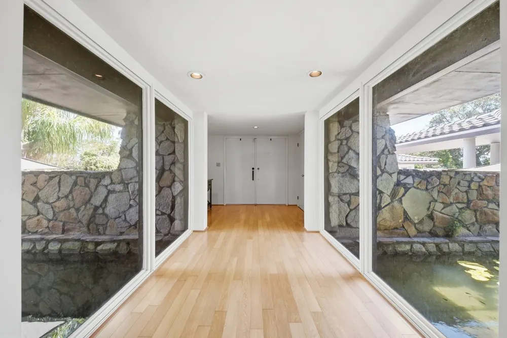 Glass-walled entry corridor with the koi pond visible on both sides
